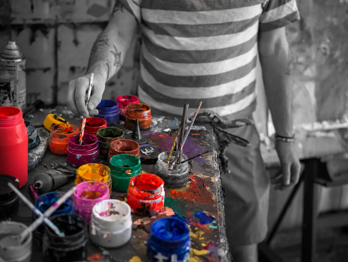 Hands, brushes and pigments: colour remains amid black and white.